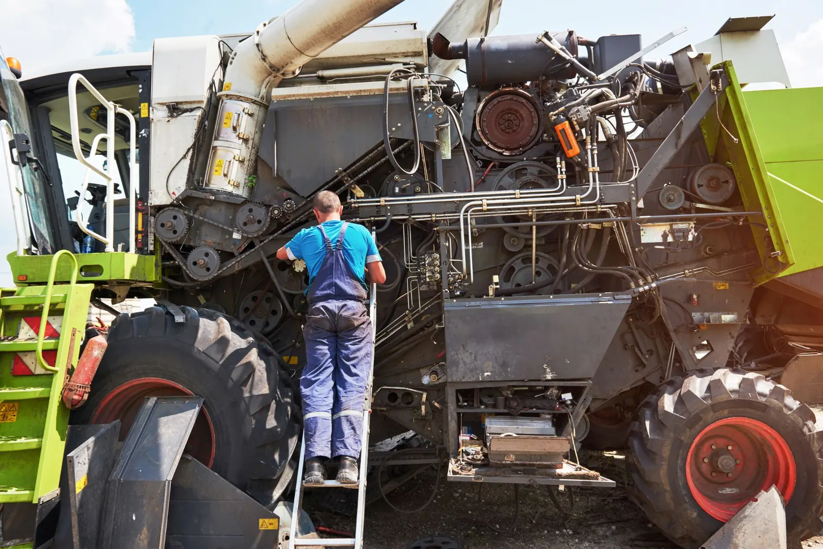 Mecânico fazendo manutenção hidráulica em colheitadeira